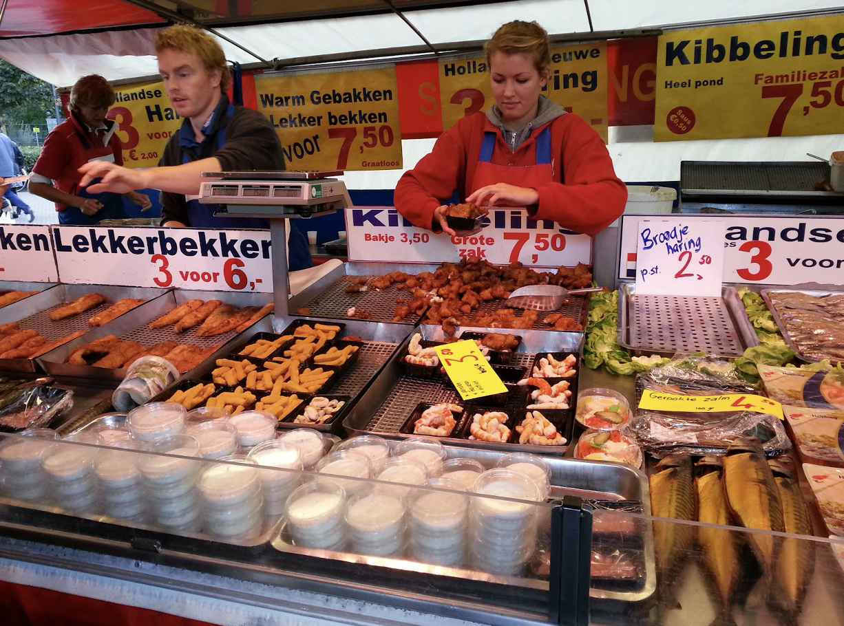 Market stall offering golden kibbeling under sunlight.